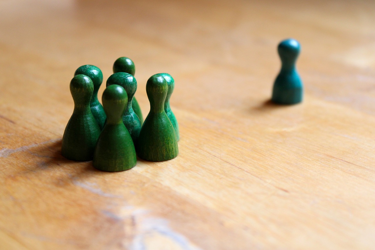 6 green playing pieces stand together in a group, one green playing piece stands apart.